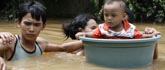 An Indonesian couple transport their son in a plastic container as they wade through the flooded streets