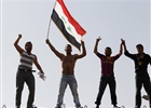 A resident waving an Iraqi flag demonstrate with fellow protesters on concrete blast walls in central Baghdad, February 25, 2011.