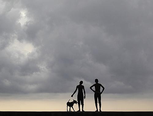 Youths stand with a dog on Havana's seafront boulevard El Malecon, in Cuba.