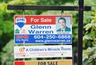 Real estate signs adorn houses and condos sold and for sale in Vancouver.