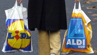 Einkauf mit Plastiktüten: Eine Person trägt jeweils eine Plastiktüte der Lebensmittel-Discounter "Lidl" und "Aldi"