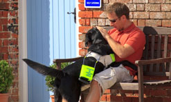 A man with his guide dog outside his front door at Ellwood Cottages, Dorset