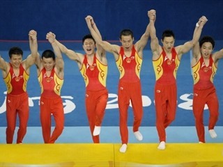 China's gymnasts jump on the podium after capturing the gold medal in men's team gymnastics.