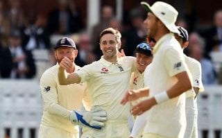 England's Chris Woakes (C) celebrates with teammates after taking the wicket of India's captain Virat Kohli
