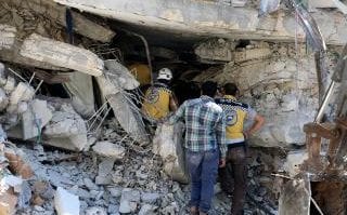 Syrian civil defense members conduct search and rescue operations at wreckage of two 6-storey buildings after a blast in Idlib